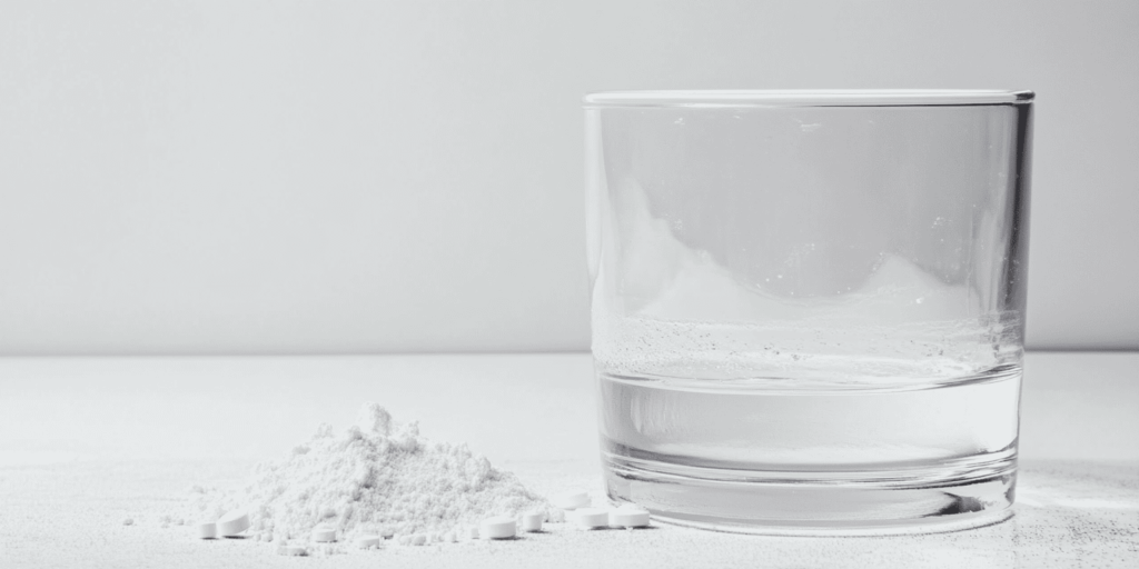 glass beside crushed tablets
