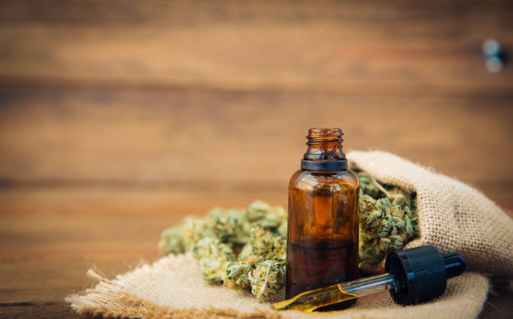 cbd oil in small bottle with hemp at back