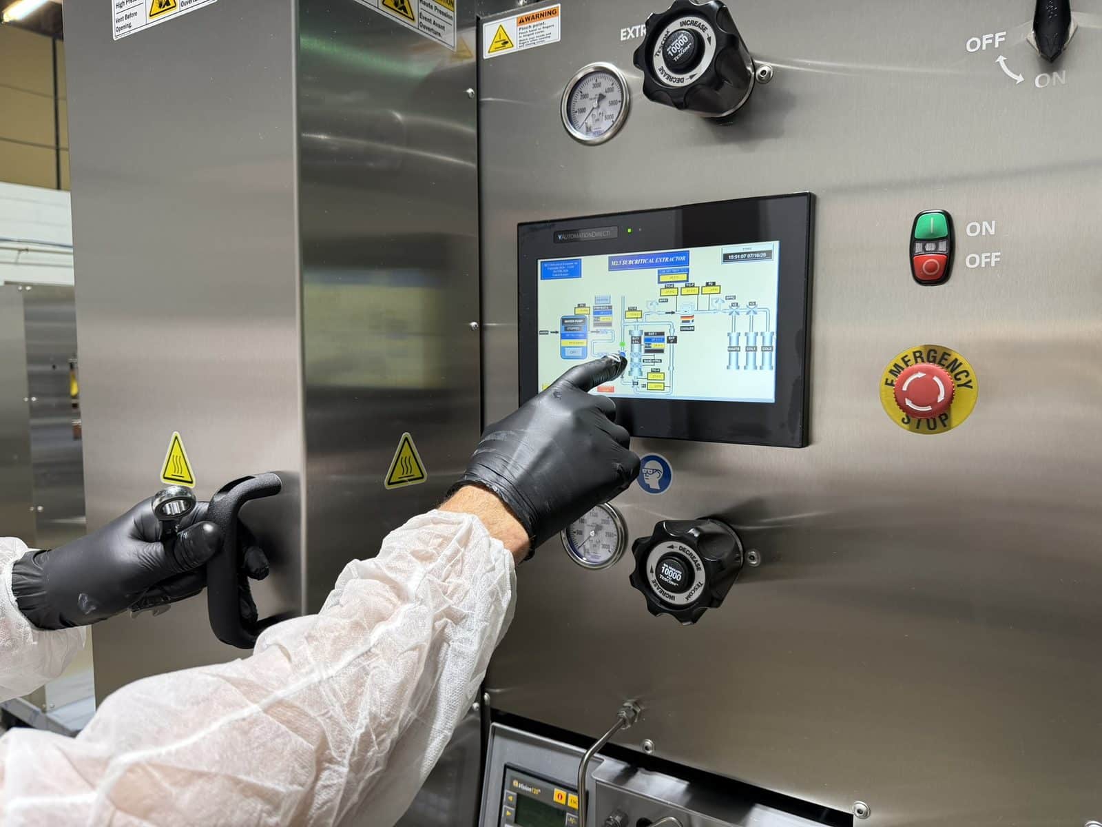 Technician in gloves operating the touchscreen of an extraktLAB subcritical water extraction system